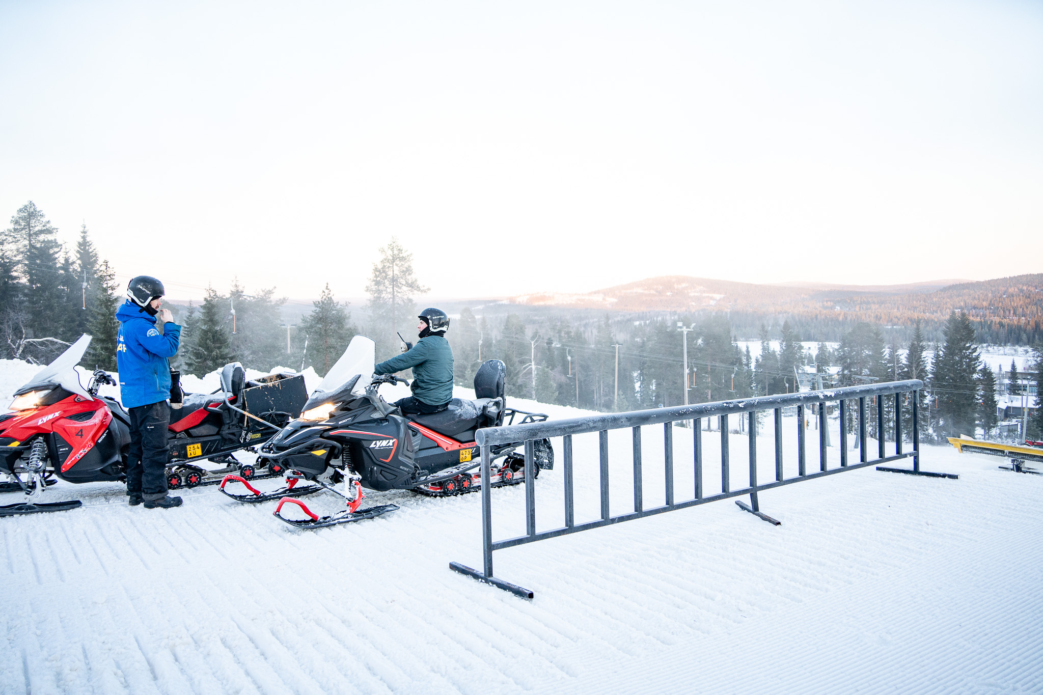 Kaksi moottorikelkkailijaa SnowParkissa reilin vieressä